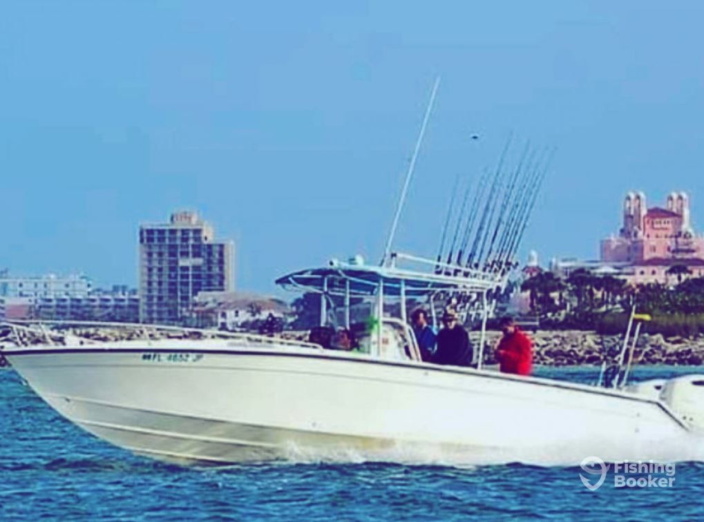 White fishing boat on water, with people, fishing rods, and city skyline in background.