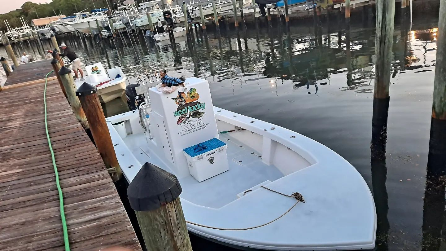 White boat docked at a pier; reflection in the water.