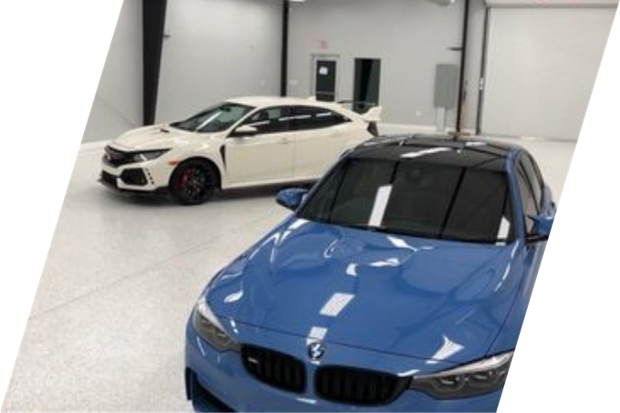 Blue BMW and white Honda Civic in a bright, indoor garage.