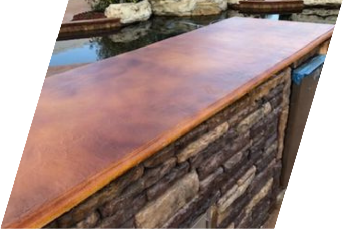 Stone bar with a stained wood-look countertop next to a pool.