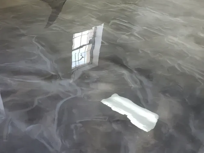 Metallic gray epoxy floor reflecting light and a window's reflection.