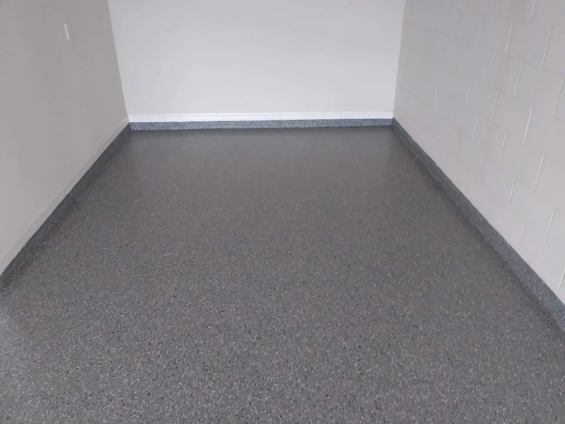 Gray speckled epoxy floor in a room with gray and white walls.