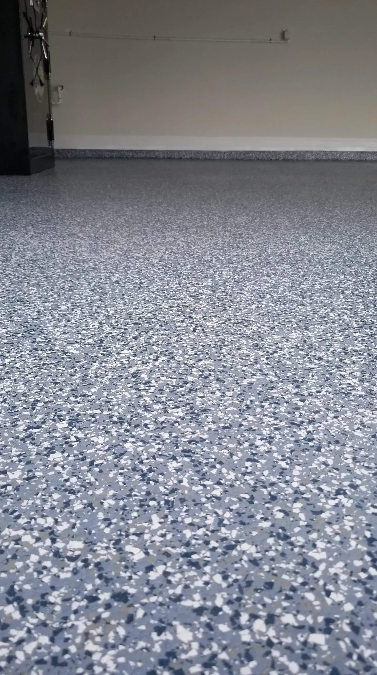 Close-up of a garage floor with a blue and white speckled epoxy finish.