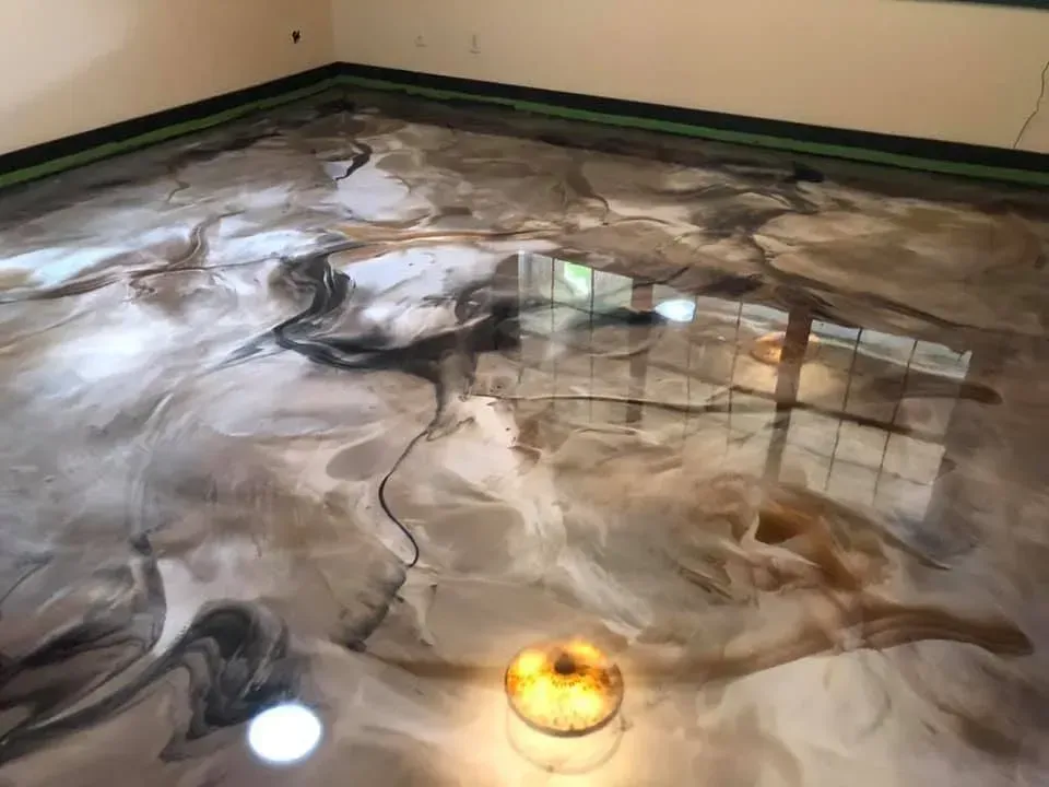 Metallic epoxy floor with swirling gold, gray, and black patterns, reflecting light.