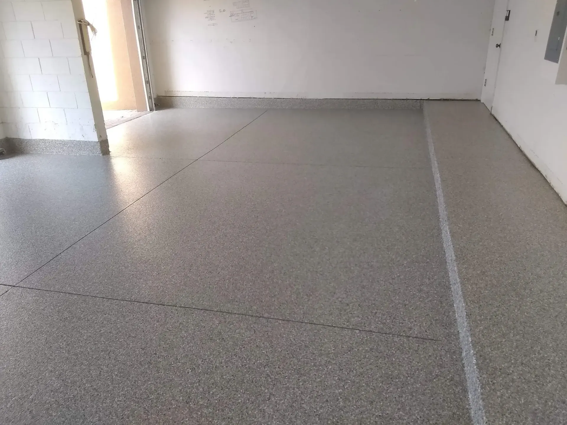 Gray speckled epoxy floor in an empty room, with white walls and a door frame.
