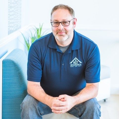 A man with a beard and a blue shirt is smiling for the camera.