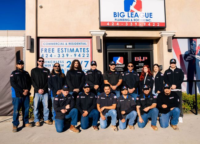 Group of people posing outside a Big League baseball facility with a “Free Estimates” sign.