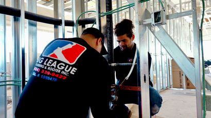 Two workers kneel inside a steel frame, measuring and inspecting construction materials.