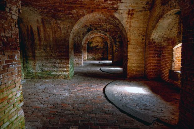 The sun is shining through the arches of an old brick building.