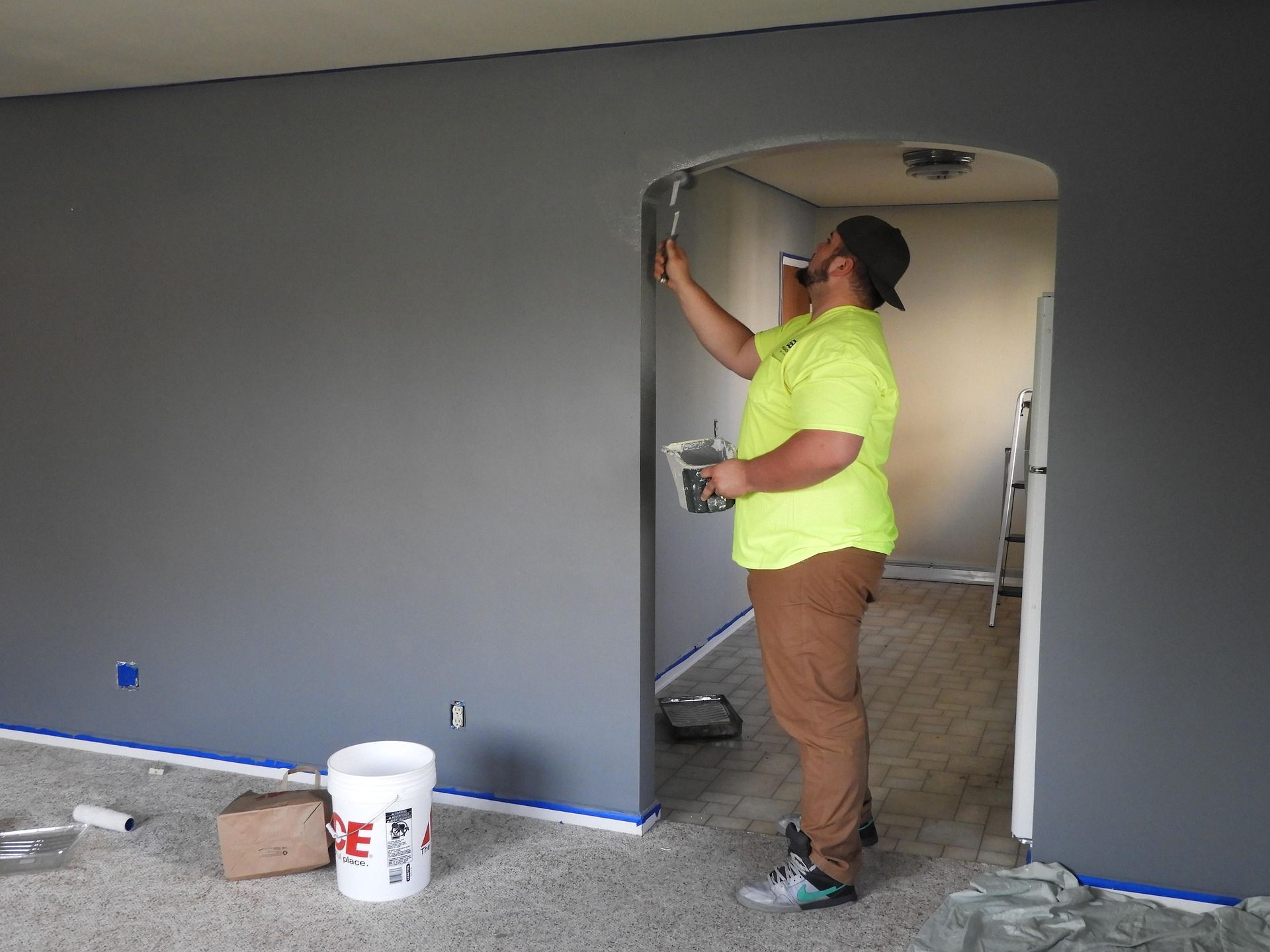 A man is painting a wall in a living room.