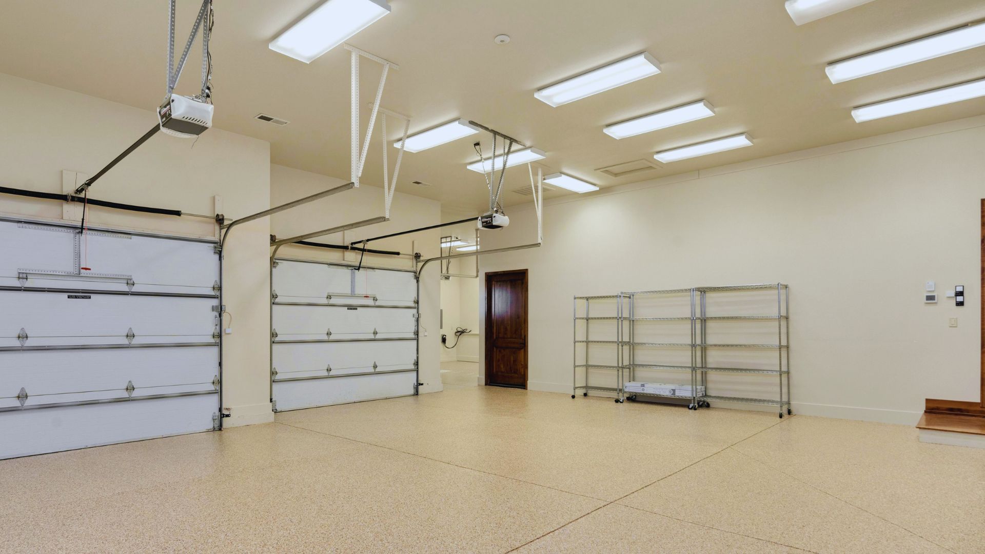 A large empty garage with two garage doors and a ceiling fan.