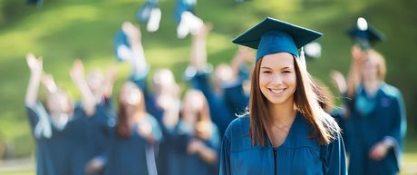 Una mujer con toga y birrete de graduación abraza a otra mujer con un diploma.