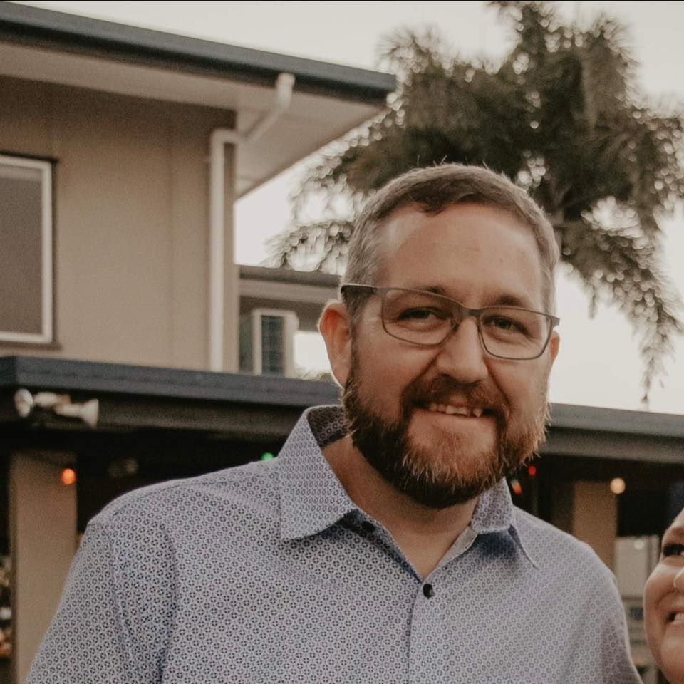 Man With a Beard and Glasses Smiling, Wearing a Blue Patterned Shirt, Outdoors — The Pest Control Guy in Ingham, QLD