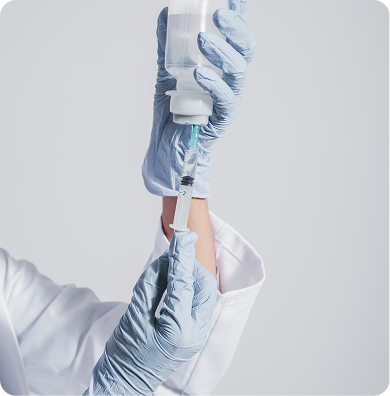 Gloved hands filling a syringe from a bottle.
