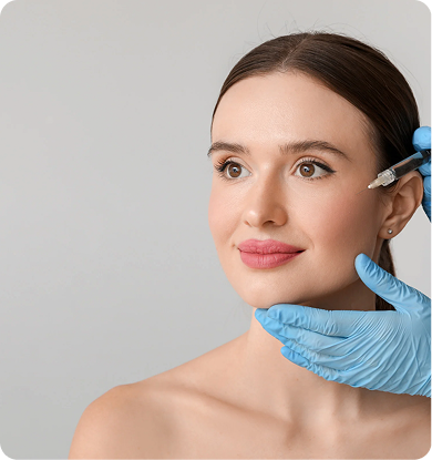 Person receiving cosmetic injections on face. Hands in gloves hold syringes, focused expression.