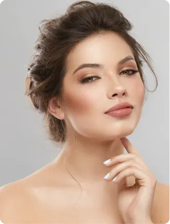 Woman with styled hair and makeup, holding chin, looking at camera.