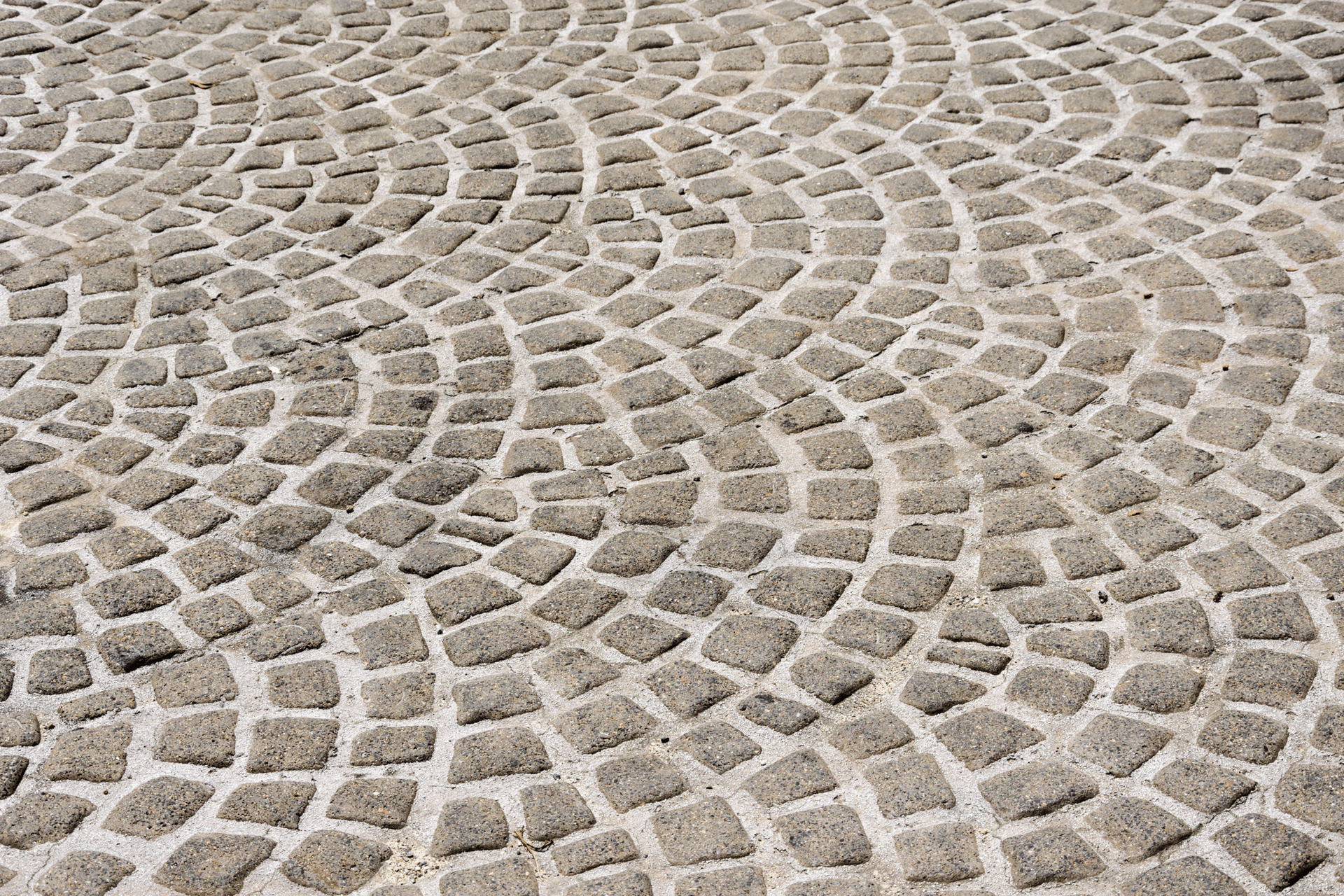 A close up of a cobblestone floor with a circular pattern.