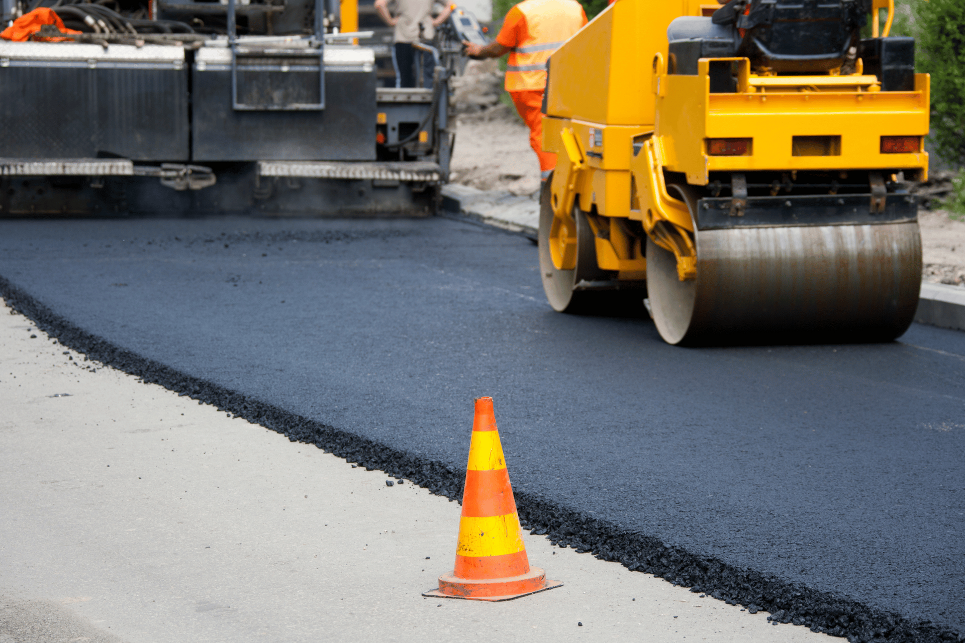 A yellow roller is rolling asphalt on a road.