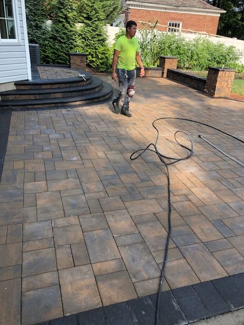 A man is standing on a brick patio next to a power cord.