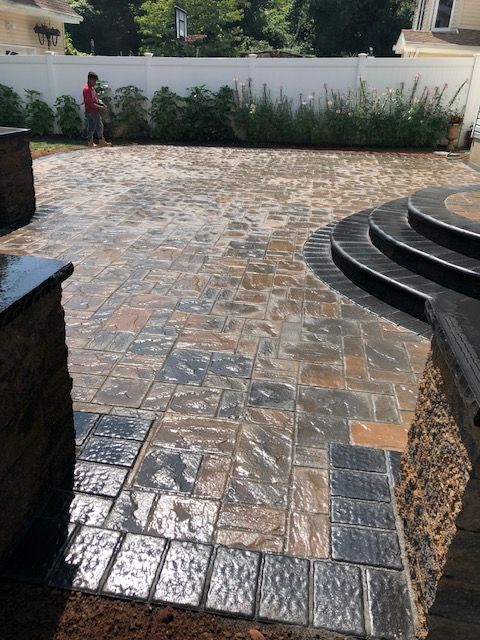 A man is standing on a brick patio next to a white fence.