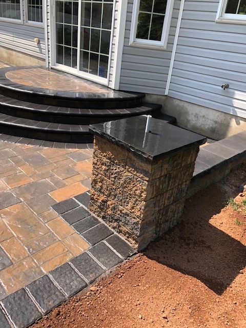 A patio with stairs and a stone pillar in front of a house