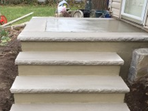 A set of concrete steps leading up to a porch.