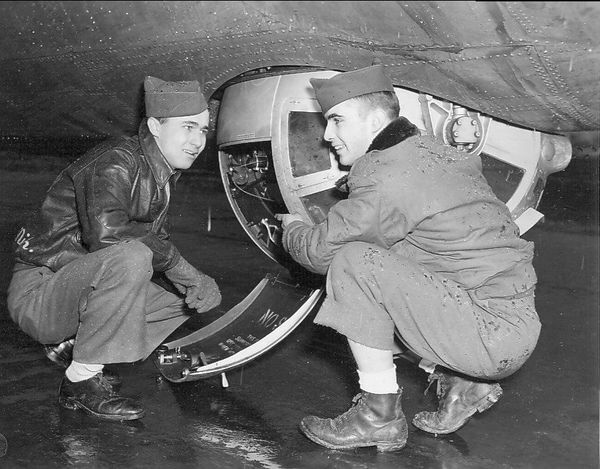 A black and white photo of two men working on an airplane