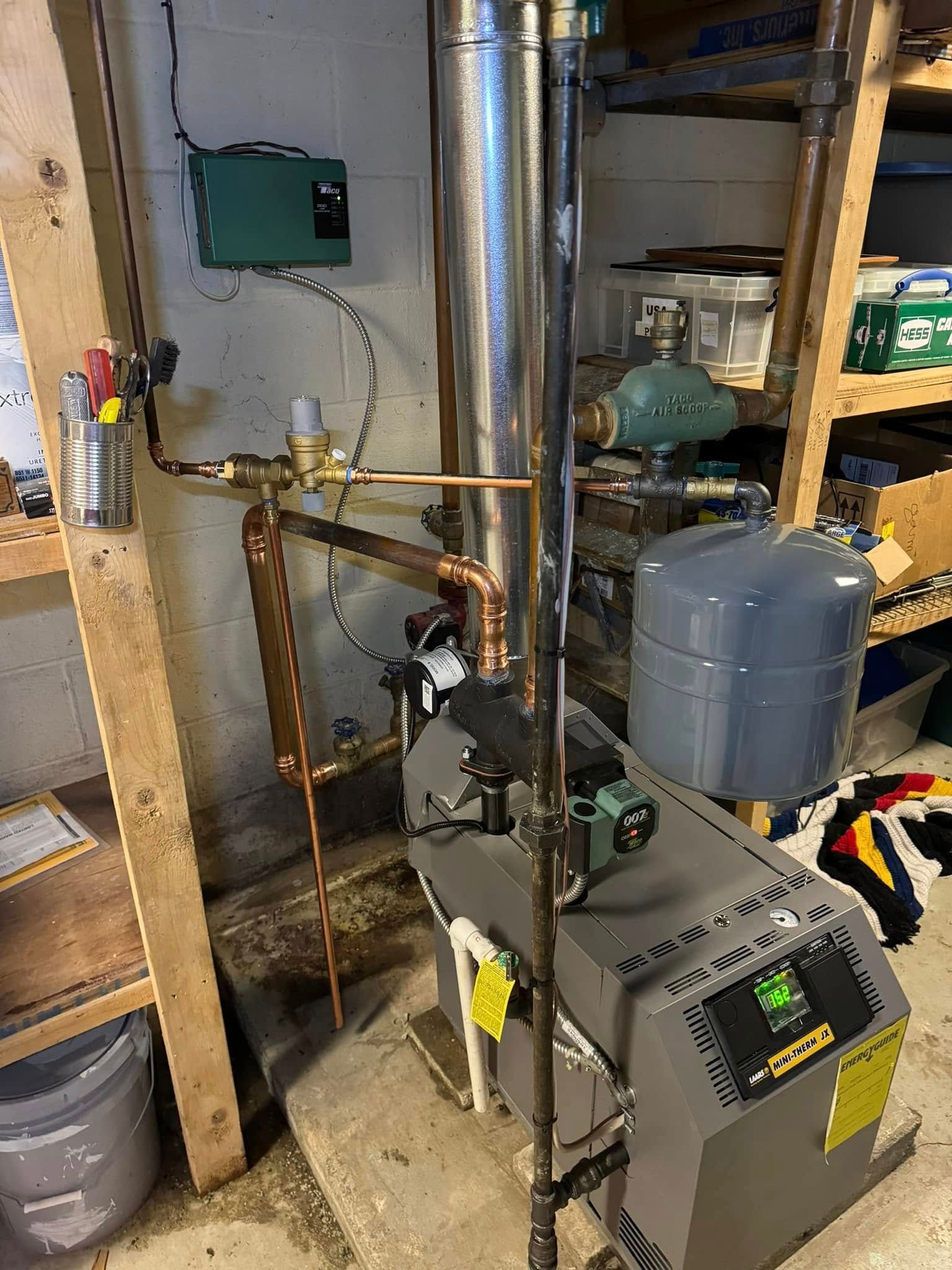 Heating system with copper pipes, a green pump, and a gray boiler in a utility room.