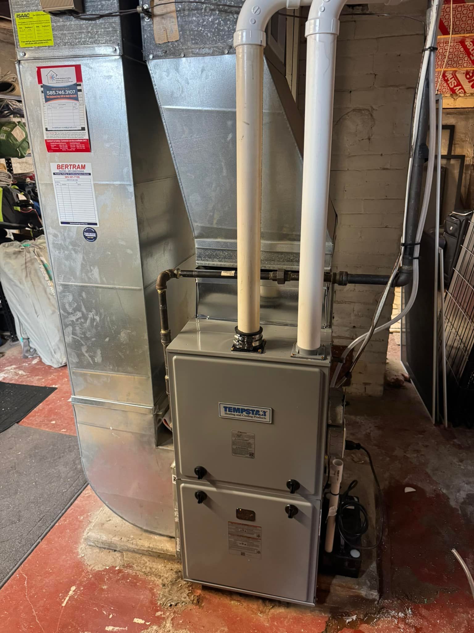 Gas furnace unit in a basement setting, with ductwork and PVC pipes.