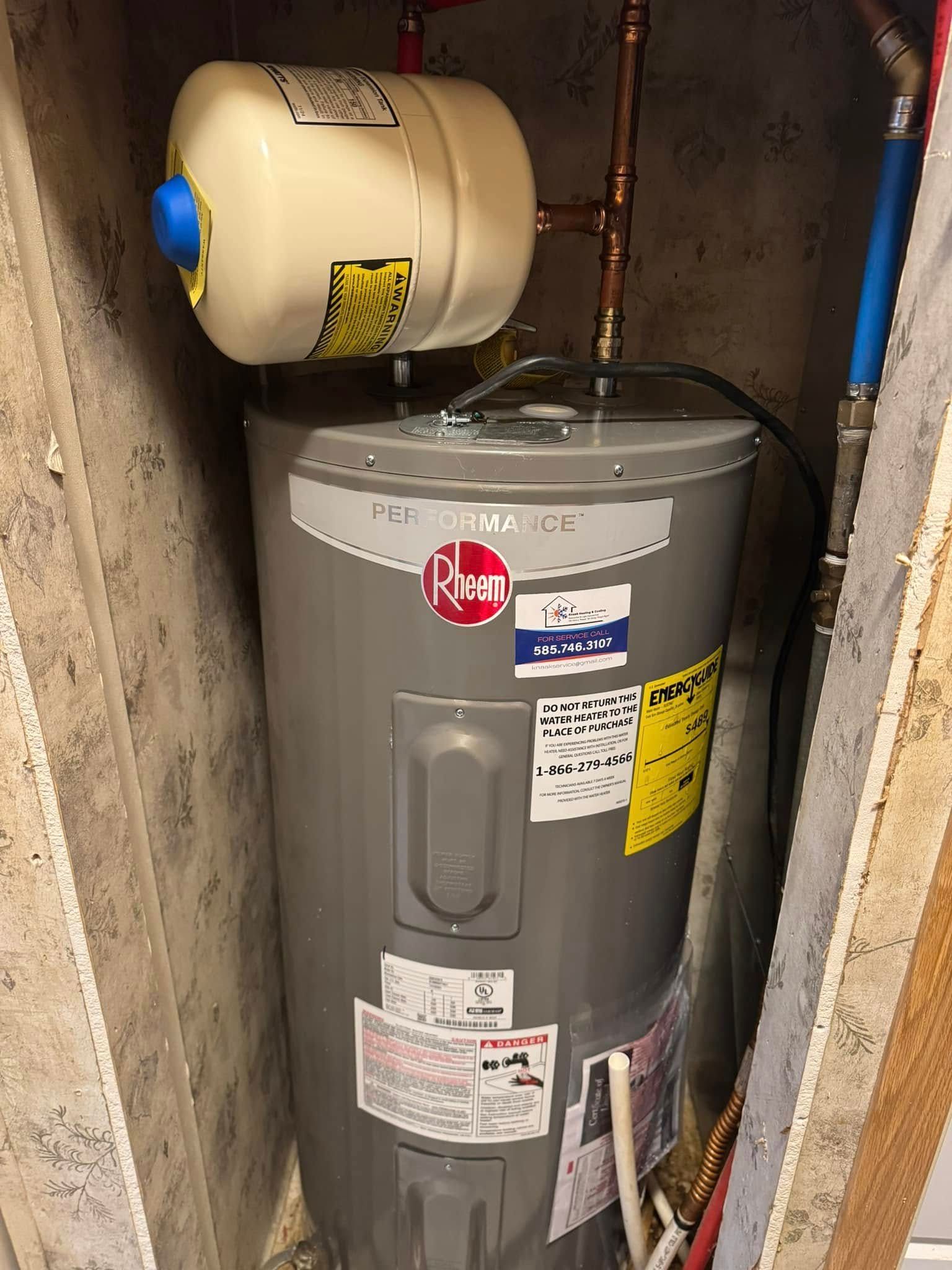 Water heater in a small enclosure, with a white expansion tank on top.
