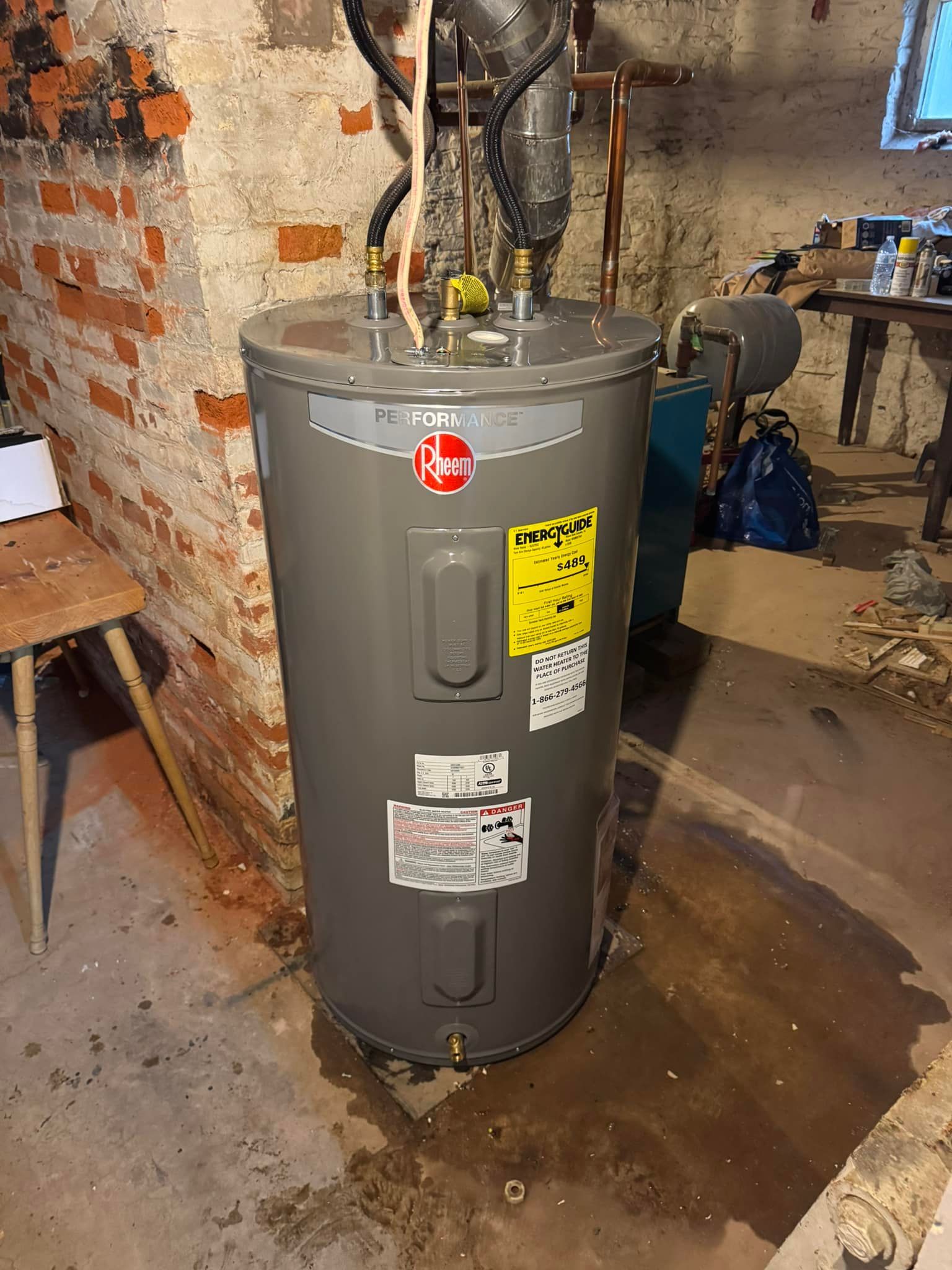 Gray Rheem water heater in a basement setting.