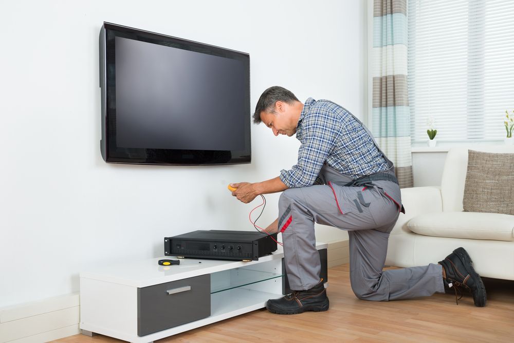 A Man is Installing a Flat Screen TV — Coffs Coast Antenna Services in Nambucca Heads, NSW