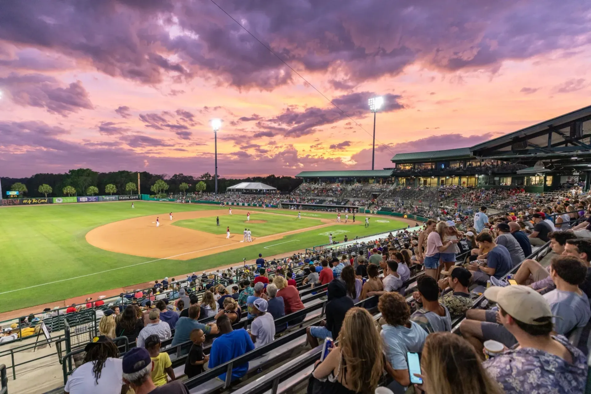 A crowd of people are watching a baseball game at a stadium.