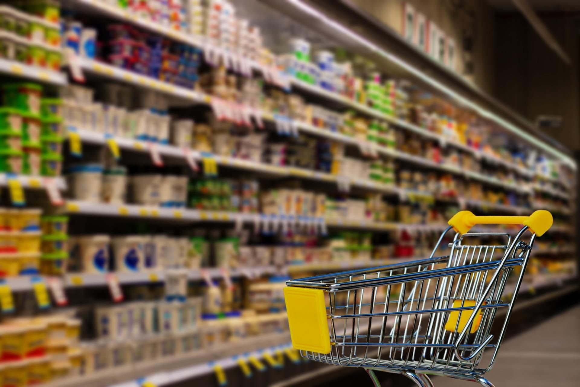 A shopping cart is sitting in a grocery store aisle.