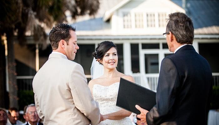 A bride and groom are holding hands during their wedding ceremony.
