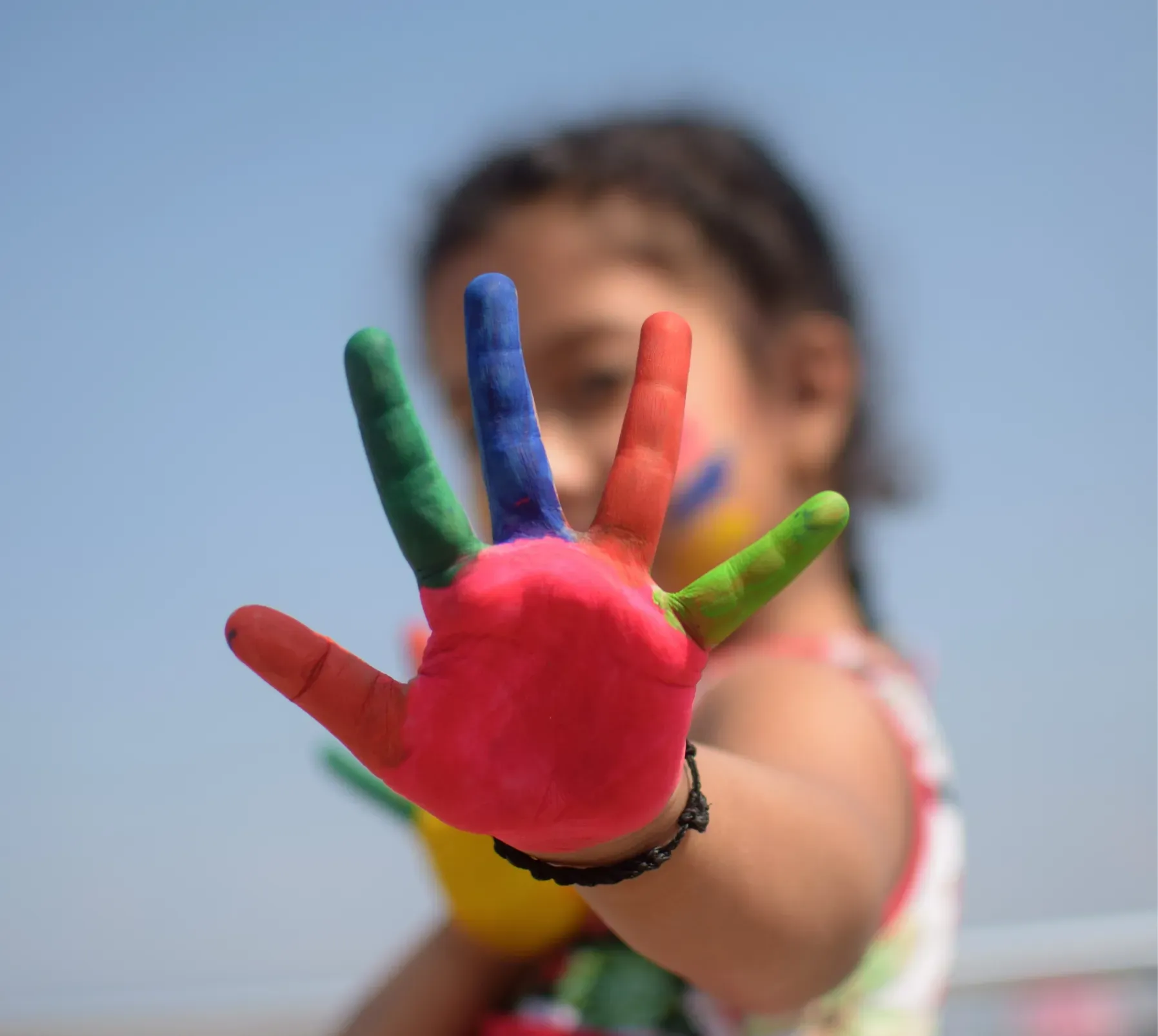 A little girl with her hands painted in different colors