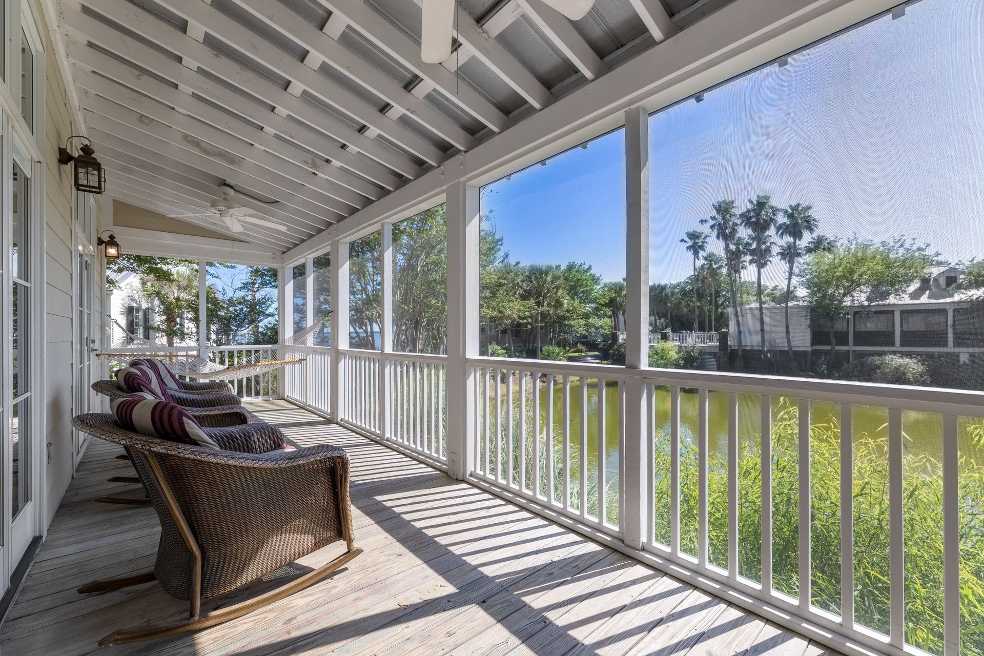 Full length screened in porch with rocking chairs, and hammock