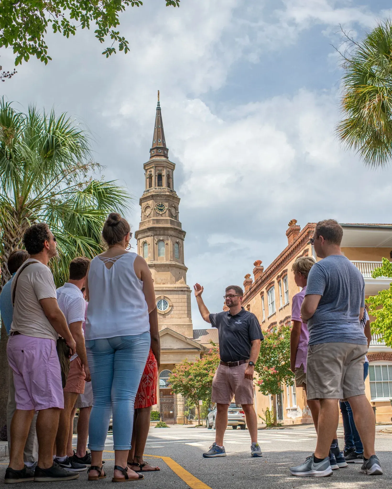 A group of people are standing on a street in front of a clock tower.