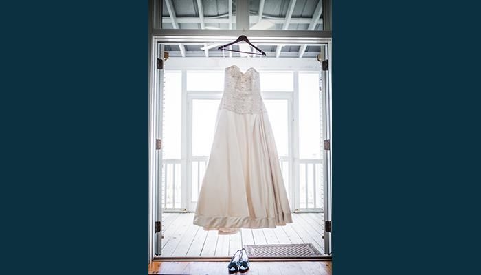 A wedding dress is hanging on a hanger in a doorway.