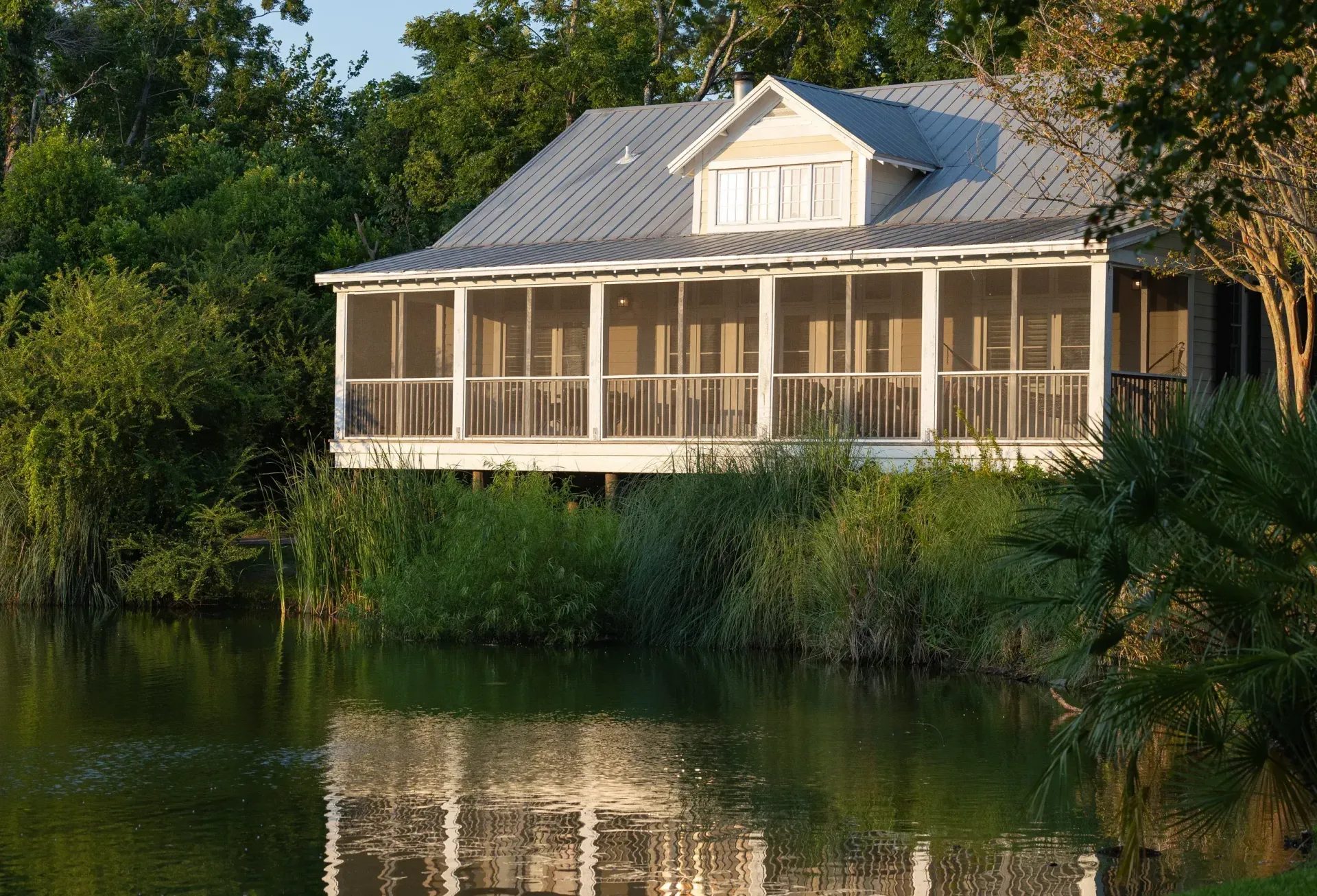 A house with a screened in porch sits next to a body of water