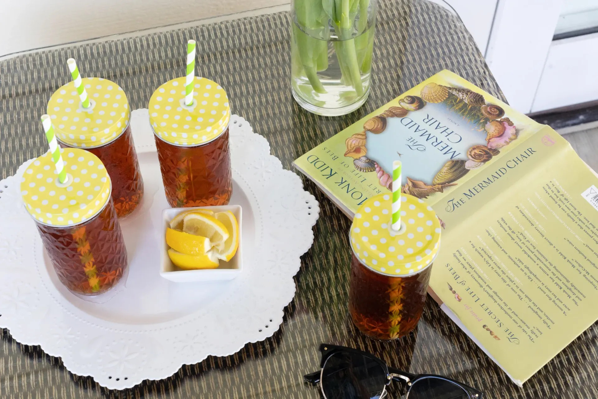Four cups of iced tea on a plate next to a book