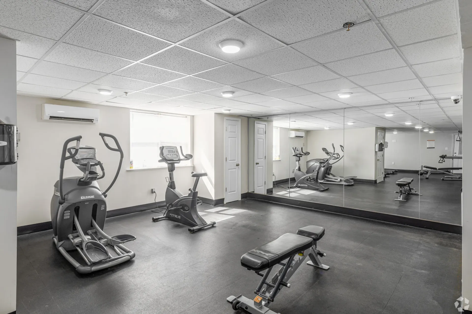 Indoor fitness center with cardio machines and a mirrored wall at Liberty Pointe in Newark, DE.