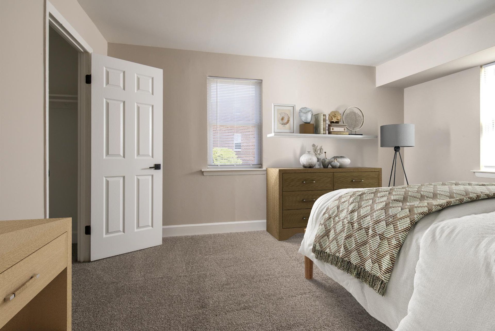 Neutral-toned bedroom with bed, dresser, shelf, and window at Liberty Pointe in Newark, DE.