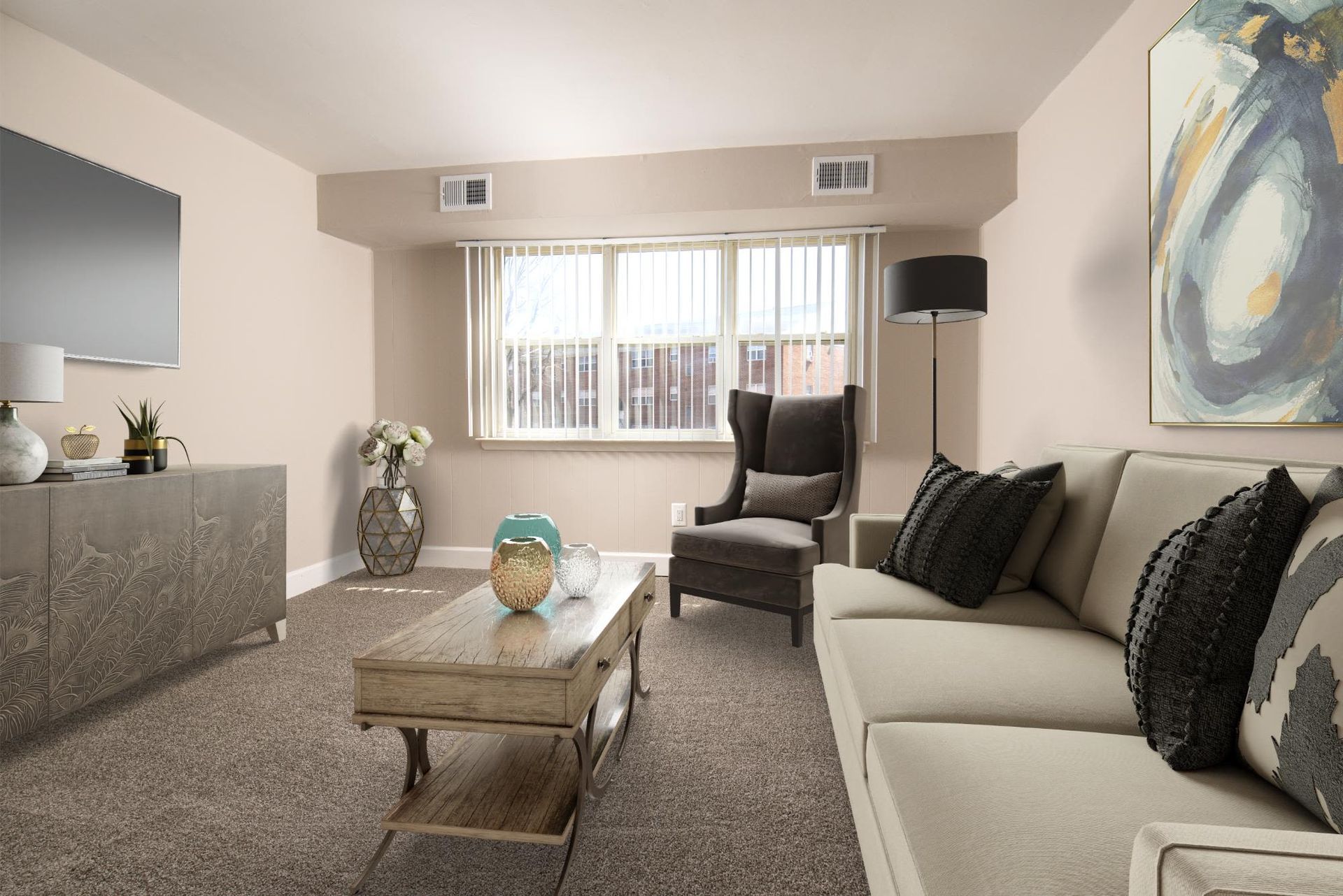 Living room in a beige apartment with sofa, armchair, coffee table, and a wall-mounted TV at Liberty Pointe in Newark, DE.