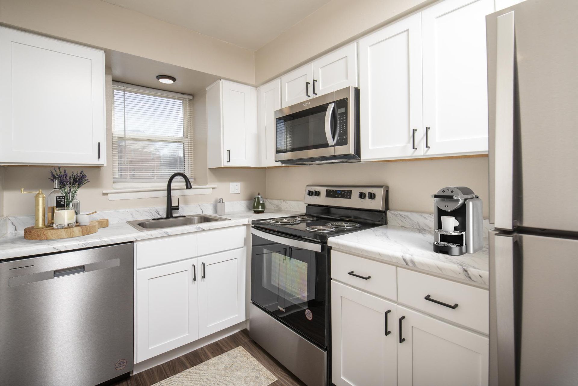 Bright kitchen in an apartment with white cabinets, marble countertops, and stainless steel appliances at Liberty Pointe in Newark, DE.