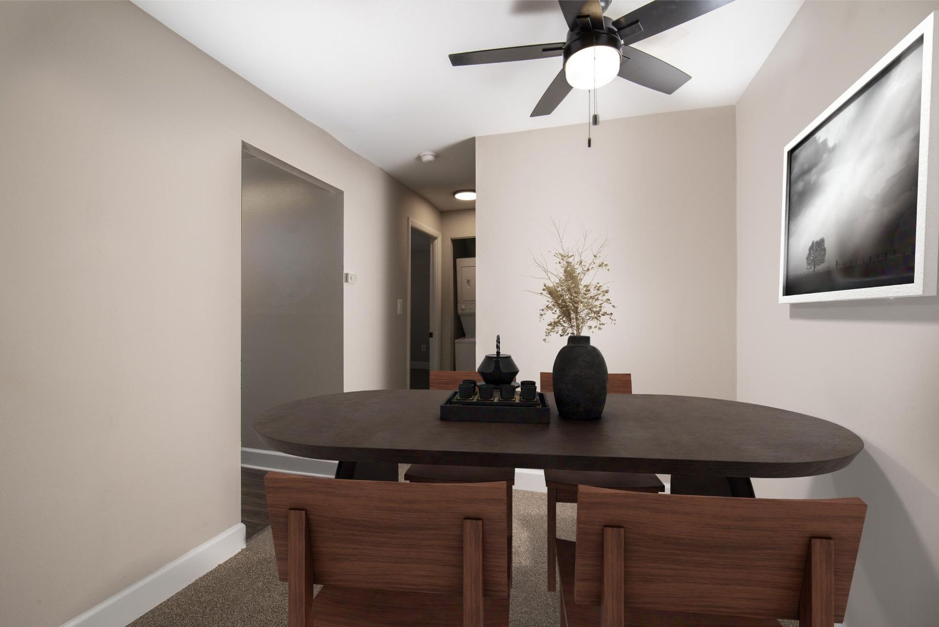 Dining area with oval table, chairs, beige walls, and a ceiling fan at Liberty Pointe in Newark, DE.