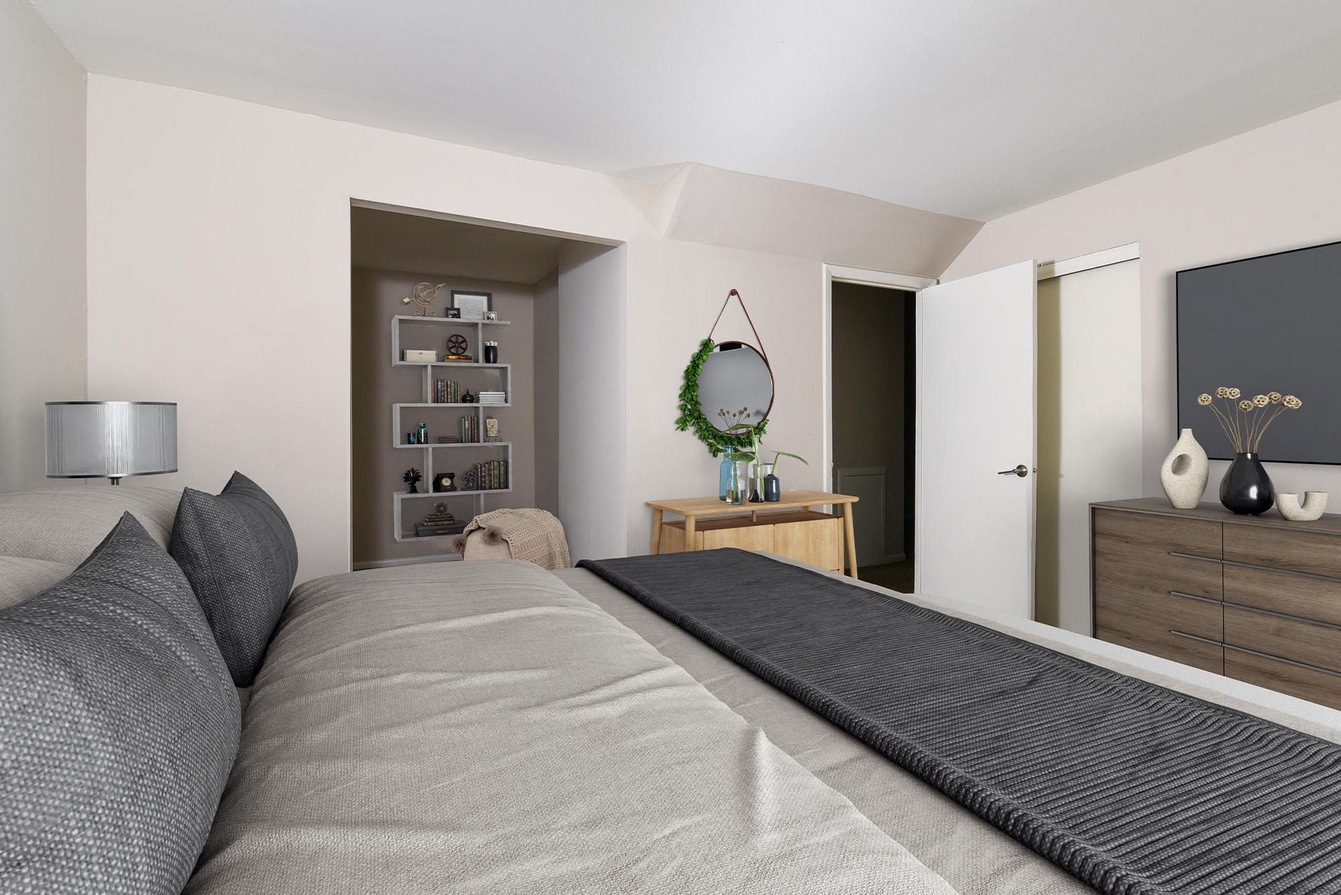 Bedroom interior with a bed featuring gray bedding, a dresser, and an open closet nook at Liberty Pointe in Newark, DE.