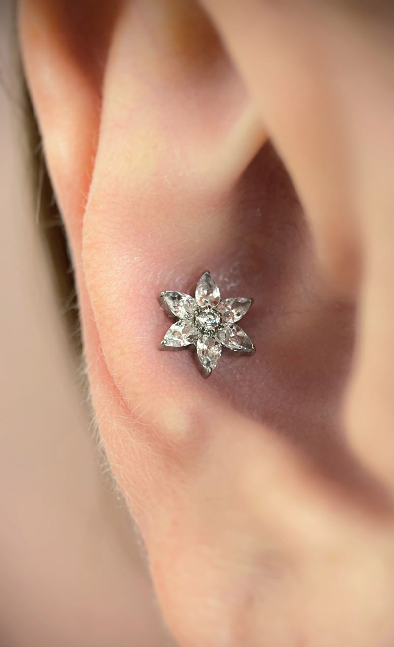 Close-up of a person's ear with a small, star-shaped, jewelled earring.