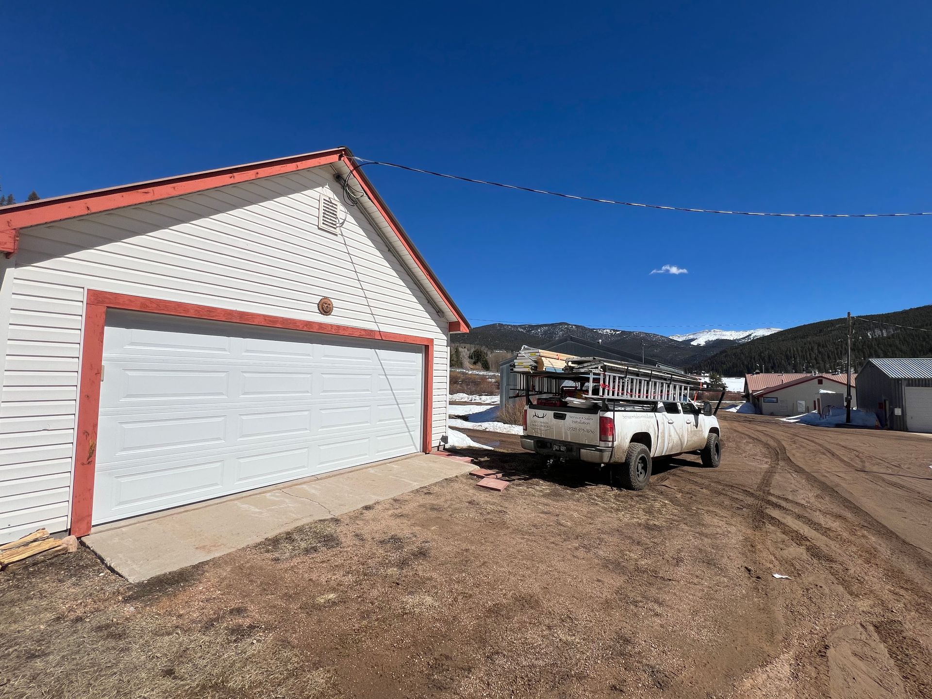 A white truck is parked in front of a garage door.