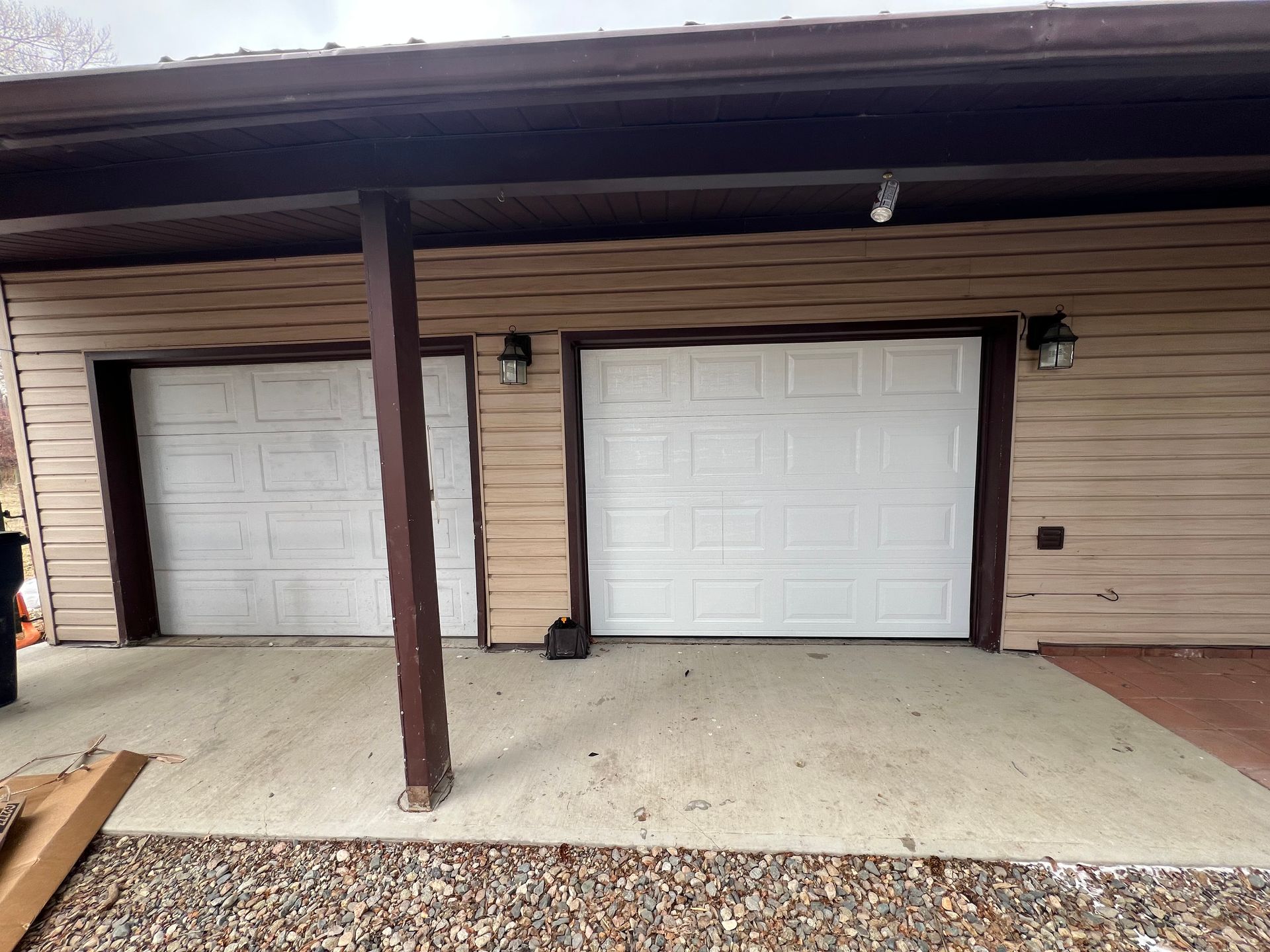 There are two garage doors on the side of a house.